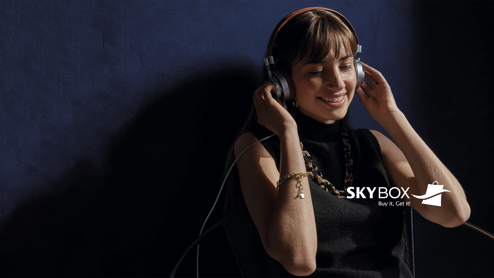 Mujer escuchando música + logo Skybox